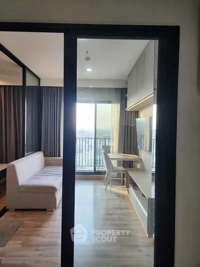 Modern apartment with open layout, featuring a cozy living area and a balcony with city views.