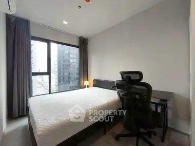 Modern bedroom with city view, featuring a comfortable bed and ergonomic chair, perfect for urban living.