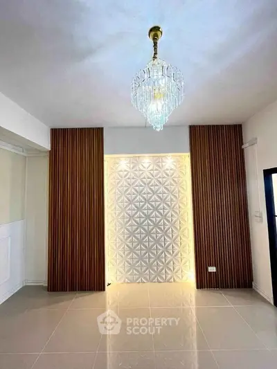 Elegant interior with modern chandelier and stylish wall paneling in a spacious room.
