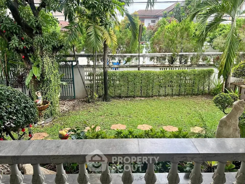 Charming garden view from a balcony with lush greenery and decorative elements.