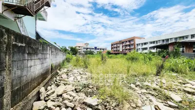 Vacant land with potential for development, surrounded by buildings under a clear blue sky.
