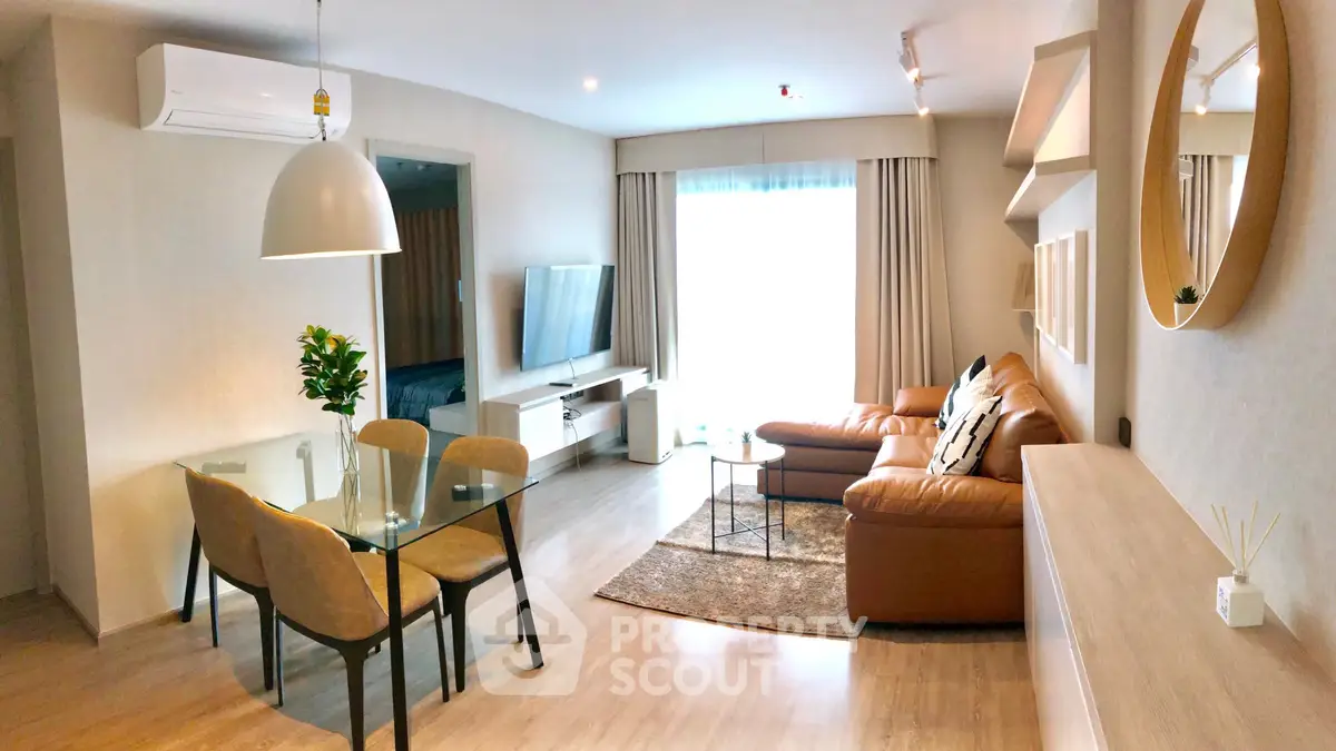 Modern living room with stylish decor and natural light, featuring a cozy leather sofa and elegant dining area.