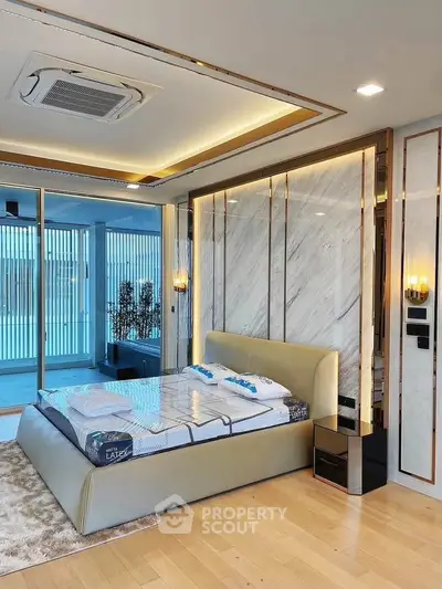 Luxurious bedroom with modern design and large windows opening to a balcony, featuring elegant lighting and decor.