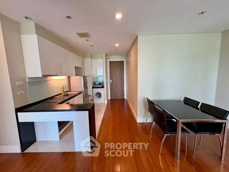 Modern kitchen with sleek dining area and hardwood floors in open layout apartment.