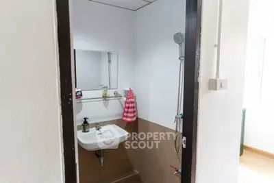 Compact bathroom with wall-mounted sink and shower in modern apartment