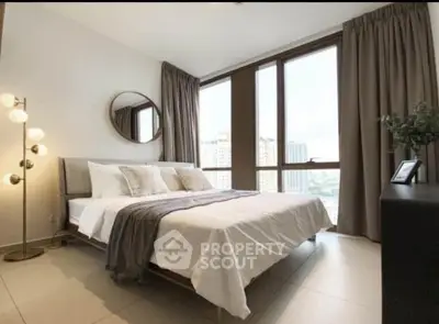 Spacious bedroom with large windows and modern decor in a high-rise apartment.