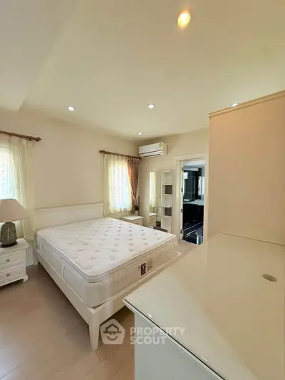 Spacious bedroom with natural light, featuring a comfortable bed and modern decor.