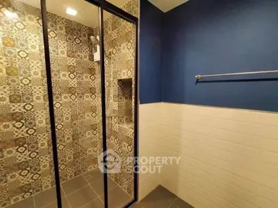 Stylish bathroom with patterned tile shower and blue accent wall