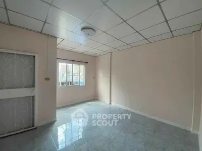 Spacious empty room with tiled floor and large window, ideal for customization.