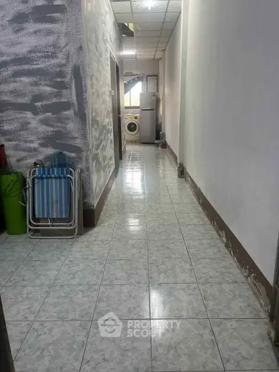 Spacious hallway with tiled flooring and laundry area featuring a washing machine.