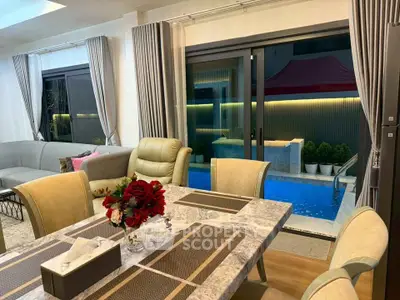 Luxurious living room with pool view, elegant dining setup, and modern decor.