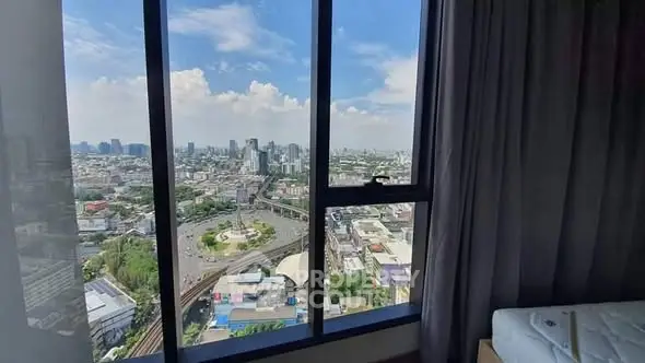 Stunning cityscape view from high-rise apartment window with clear blue sky.