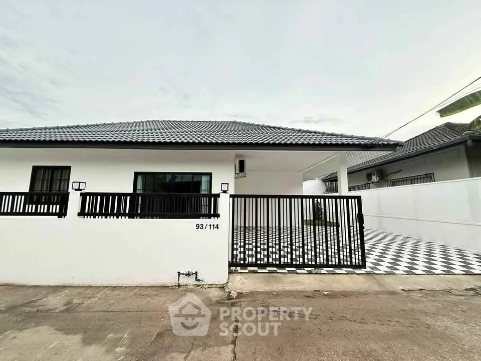 Modern single-story house with sleek black and white exterior and gated driveway.