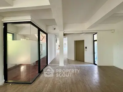 Spacious modern interior with glass partition and elevator access, ideal for office or commercial use.