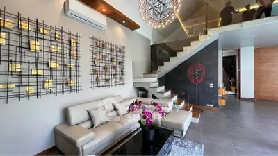 Modern living room with stylish decor and staircase, featuring elegant lighting and contemporary furniture.