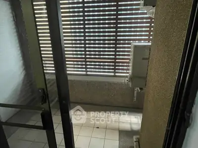 Cozy enclosed balcony with tiled flooring and slatted blinds for privacy.