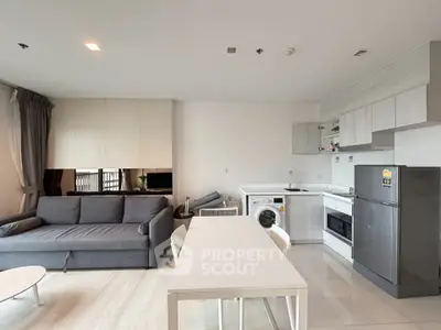 Modern open-plan living room with kitchen, featuring sleek furniture and appliances.