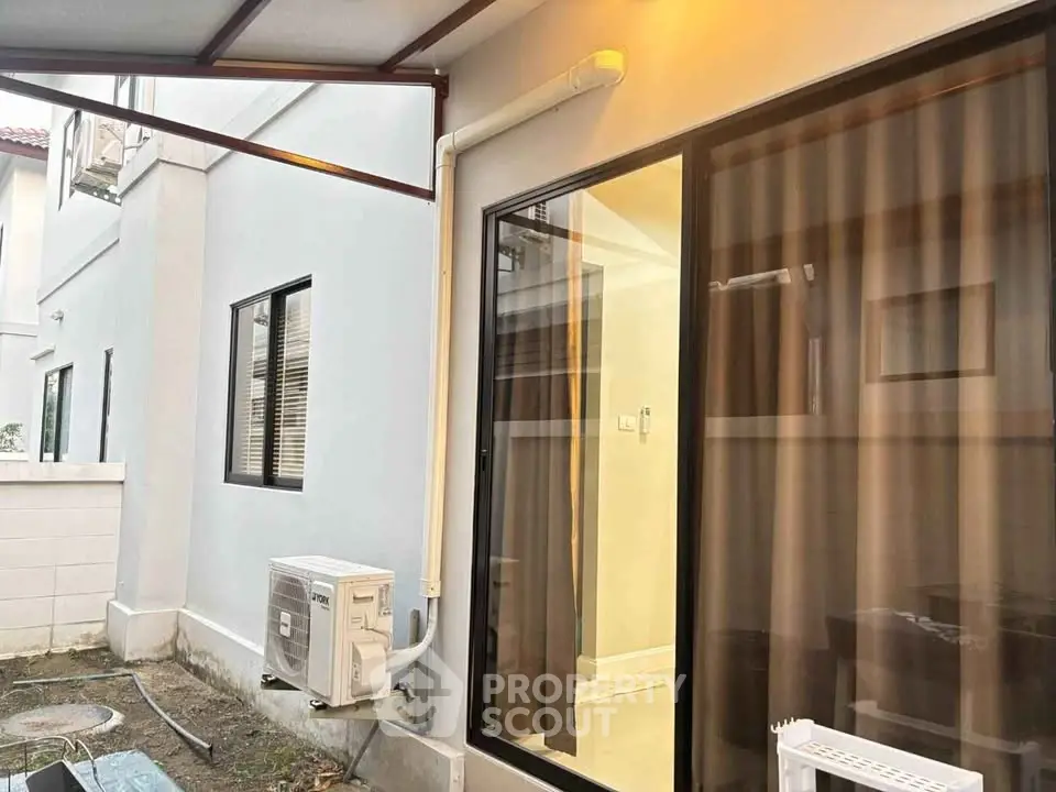 Modern exterior view of a house with sliding glass door and air conditioning unit.