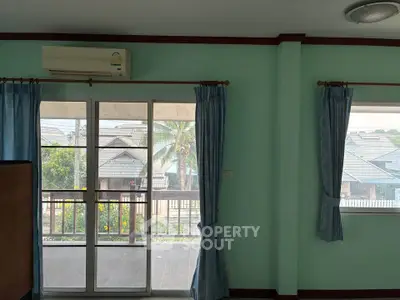 Spacious living room with large windows and balcony view in a serene neighborhood.