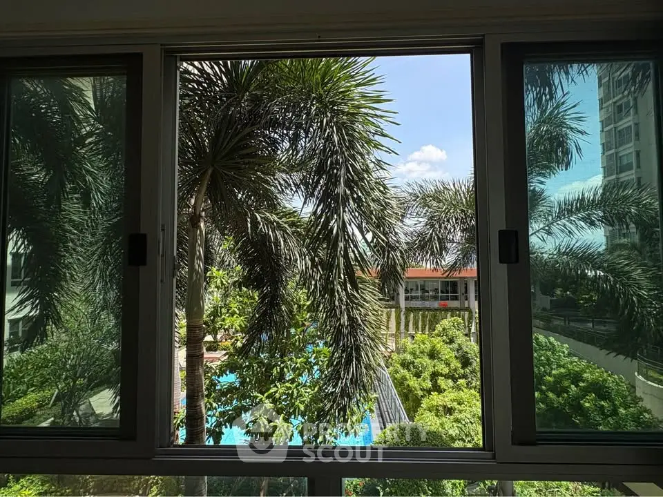 Stunning view of lush garden and pool from a window, perfect for relaxation and leisure.