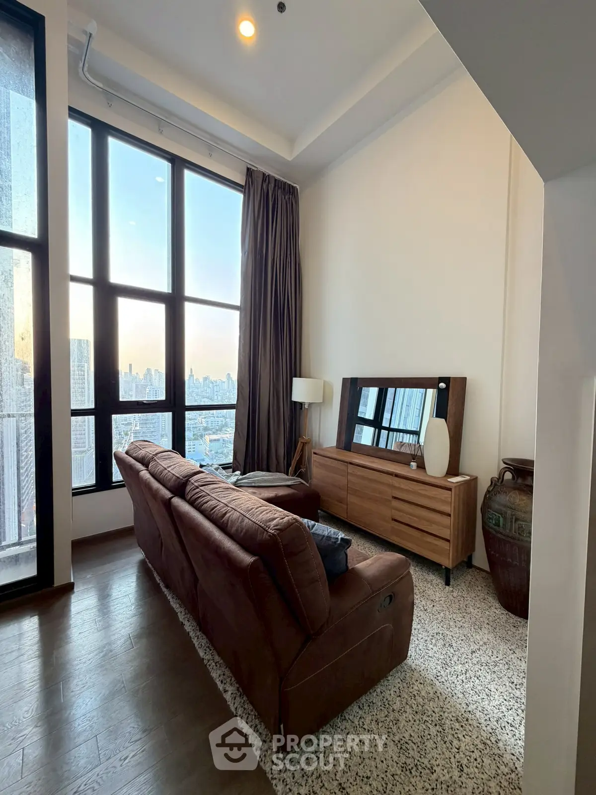 Luxurious living room with stunning city view, featuring elegant furniture and floor-to-ceiling windows.