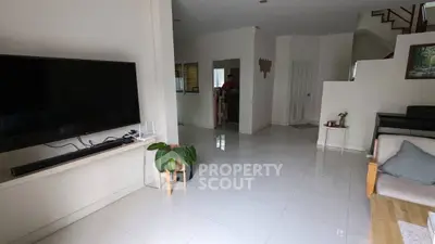 Spacious living room with modern TV setup and elegant white flooring.