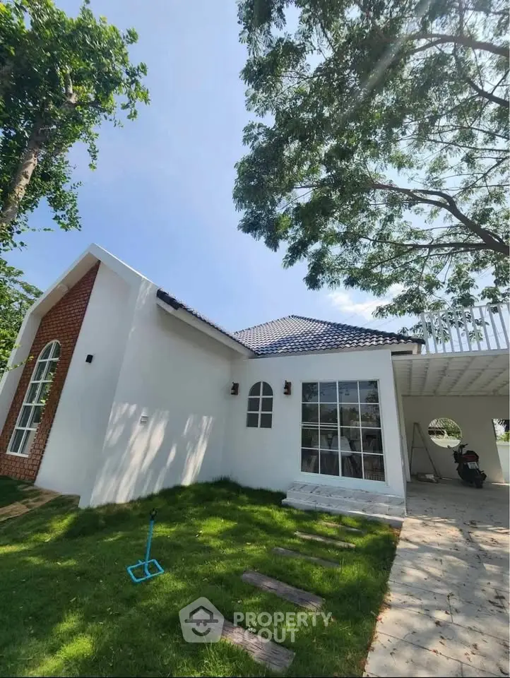 Charming modern house with blue roof, large windows, and lush green lawn under clear sky.