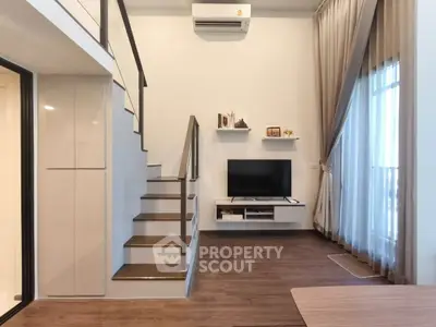 Modern living room with loft design, featuring a sleek staircase, wall-mounted TV, and large windows with curtains.