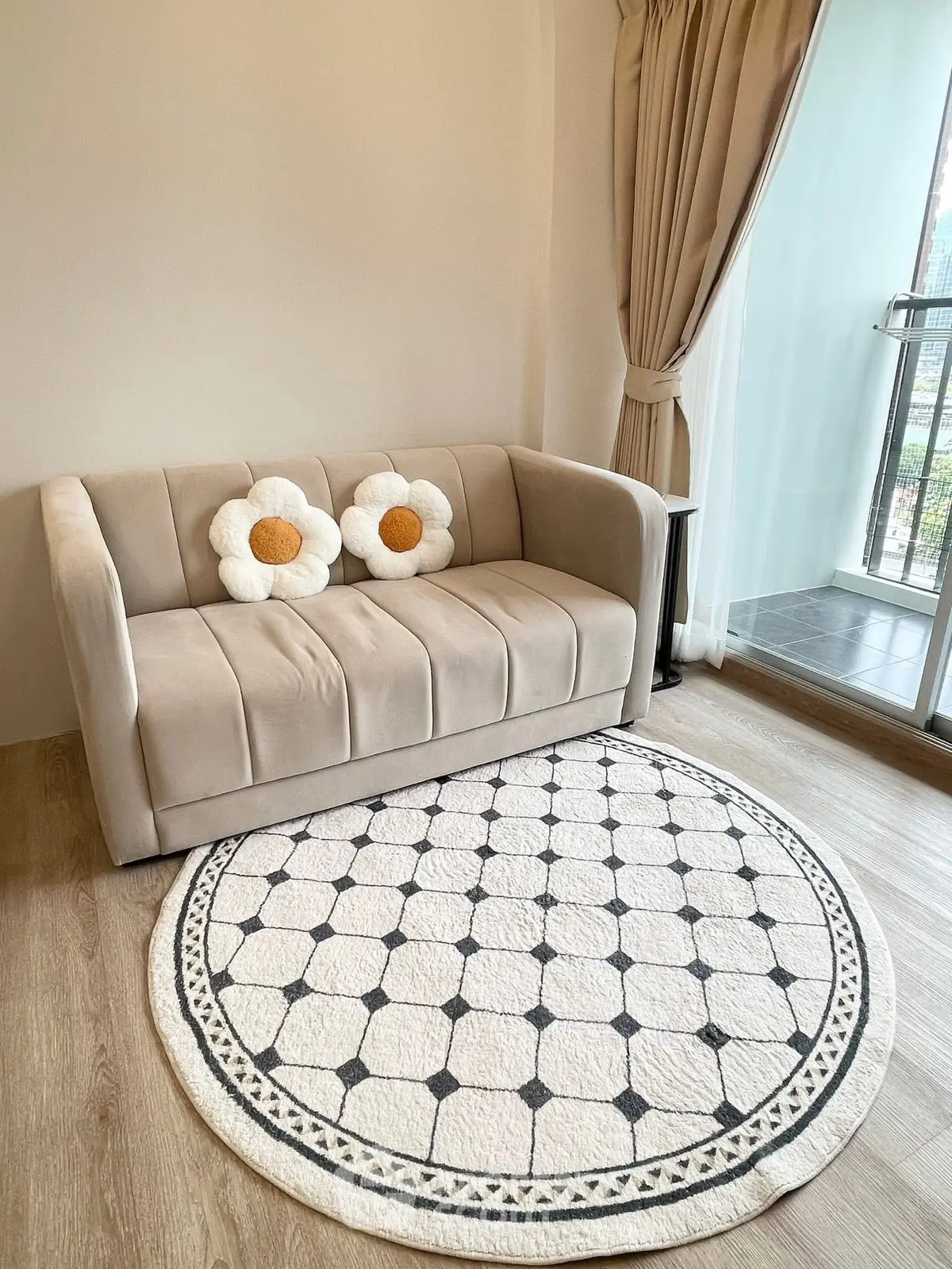 Cozy living room with plush sofa and floral cushions, elegant round rug, and balcony view.