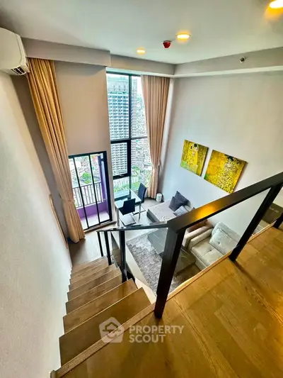 Stunning duplex living room with high ceilings and city view from balcony.