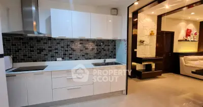 Modern kitchen with sleek white cabinets and stylish backsplash in open layout apartment.