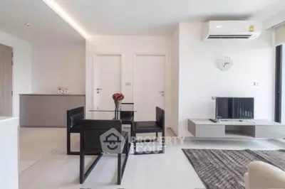 Modern living room with sleek furniture and minimalist design, featuring a glass dining table and wall-mounted TV.
