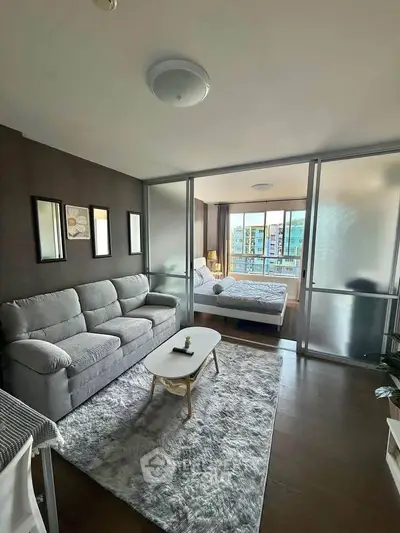 Modern living room with cozy sofa and stylish decor, featuring a view into a chic bedroom.