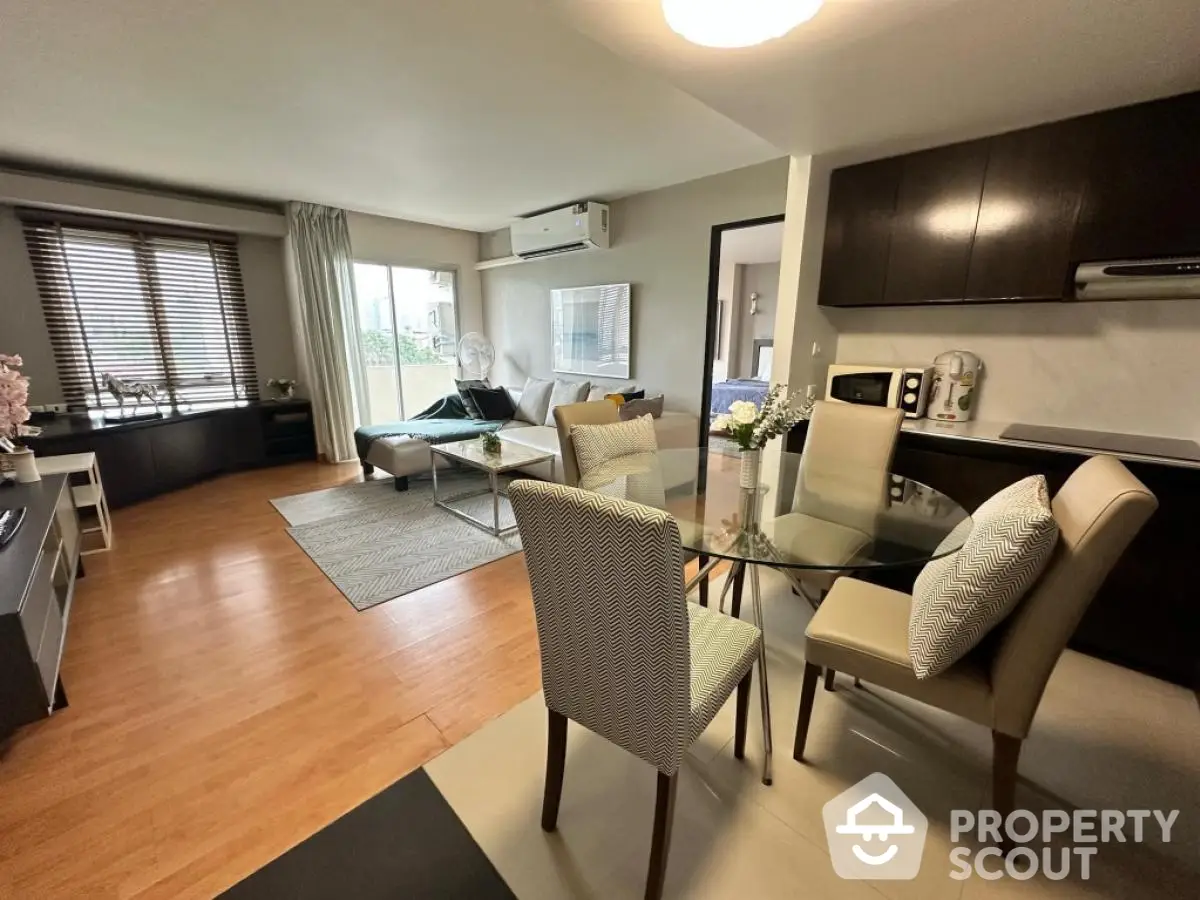 Modern open-plan living room with dining area and kitchen, featuring stylish decor and natural light.