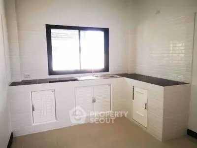 Modern kitchen with sleek white cabinetry and large window for natural light.