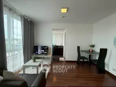 Modern living room with wooden flooring, stylish furniture, and natural light from large windows.