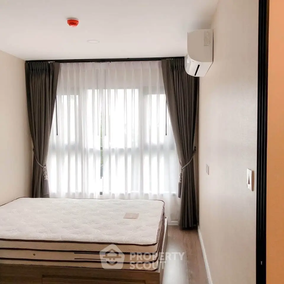 Modern bedroom with large window, elegant curtains, and air conditioning unit.