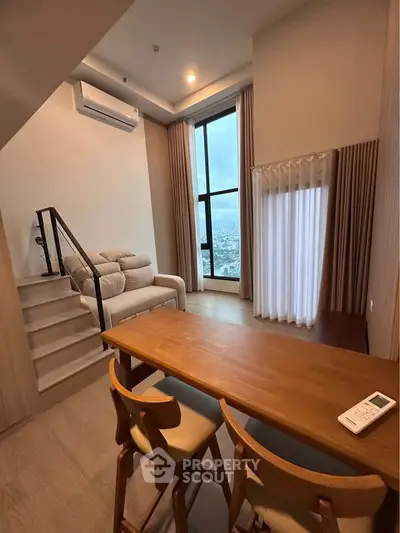 Modern loft apartment with high ceilings and city view, featuring cozy living area and dining space.