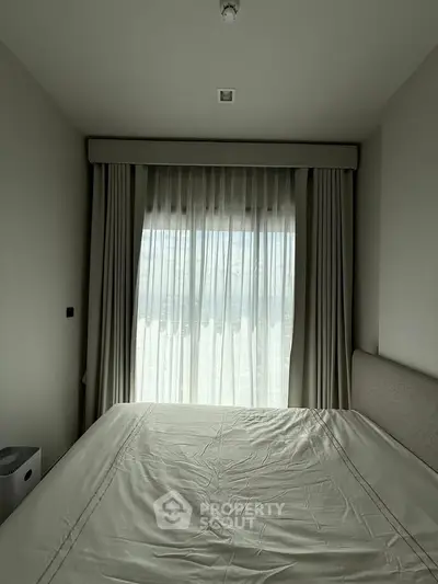 Cozy bedroom with large window and elegant curtains, perfect for natural light lovers.