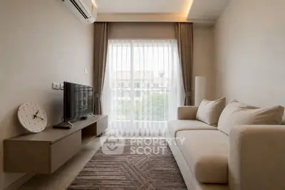 Modern living room with large window, cozy sofa, and wall-mounted TV in a stylish apartment.