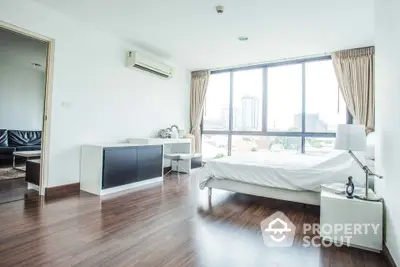 Spacious bedroom with large windows offering city views and modern furnishings.