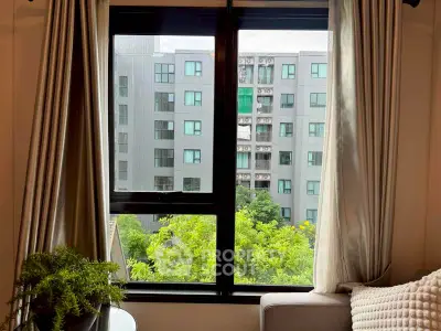 Cozy living room with a view of modern apartment building through large window.