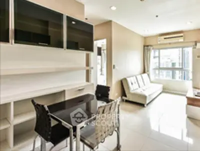 Modern living room with sleek furniture and large window offering city views.