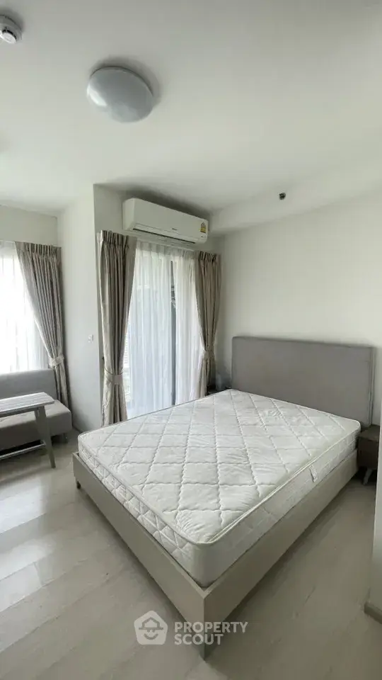 Modern bedroom with large windows and natural light, featuring a comfortable bed and minimalist decor.