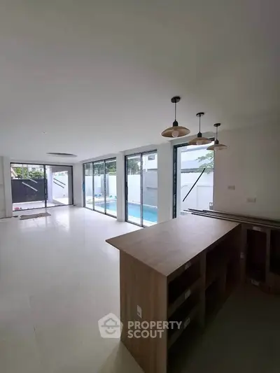 Spacious open-plan living area with pool view and modern kitchen island
