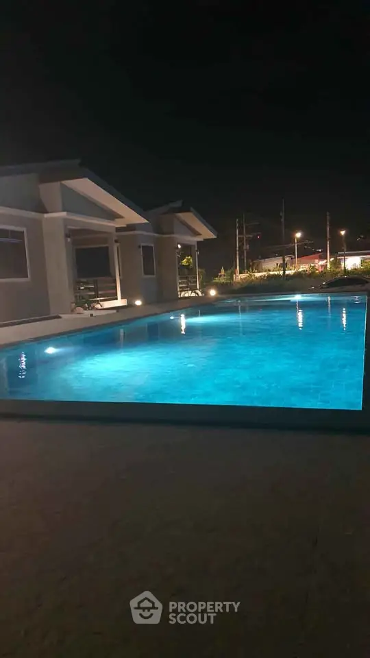 Stunning night view of illuminated swimming pool in modern residential complex.
