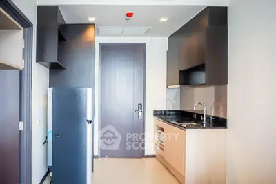 Modern compact kitchen with sleek cabinetry and built-in appliances in a stylish apartment.