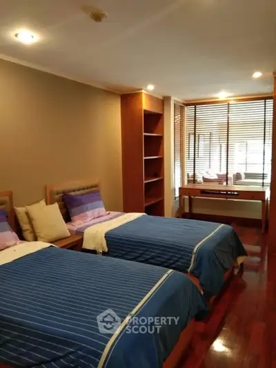 Spacious bedroom with twin beds and natural light from large windows.