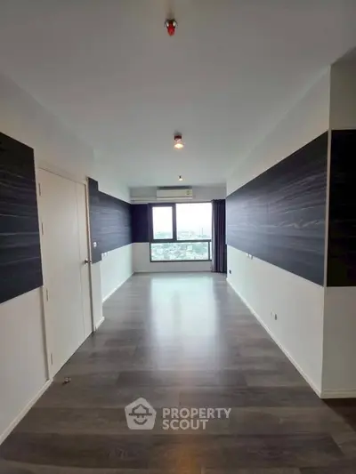 Spacious modern living room with dark wood flooring and city view.