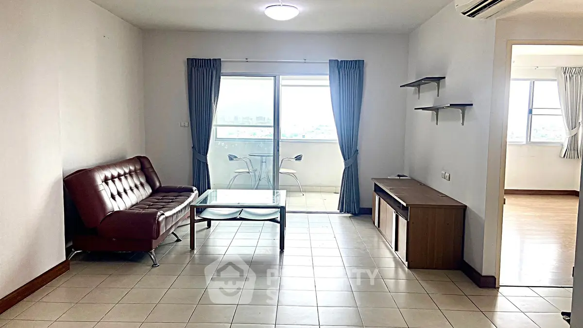 Spacious living room with modern furniture and balcony view, perfect for urban living.